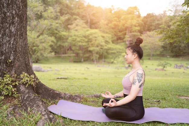 Aziatische tattoo jonge vrouw doet yoga in het park