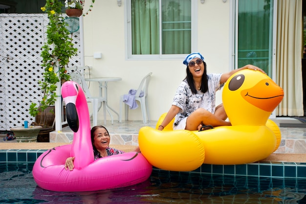 Foto aziatische thaise vrouw speelt en zwemt dierlijk speelgoedrubber drijvend op het zwembadwater in het resort in thailand