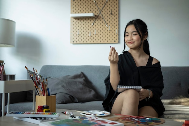 Aziatische tienermeisje tekening foto huiswerk op bank Kunstonderwijs creativiteit tiener hobby's