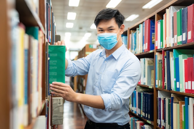 Aziatische universiteitsstudentjongen die medisch gezichtsbeschermend masker draagt voor bescherming tegen virusziekte