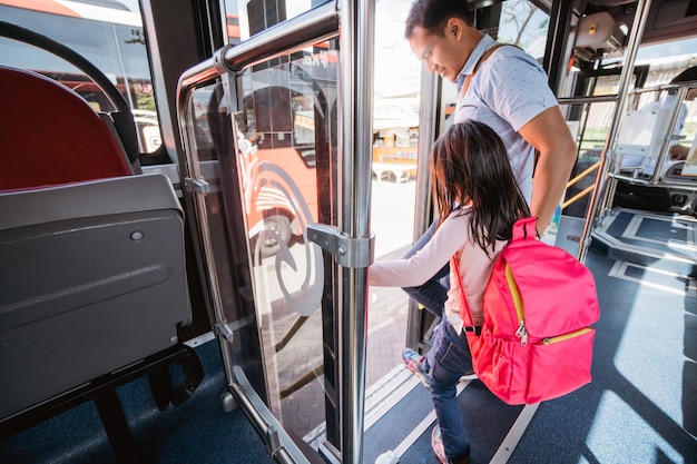 Aziatische vader brengt zijn dochter naar school met het openbaar vervoer per bus