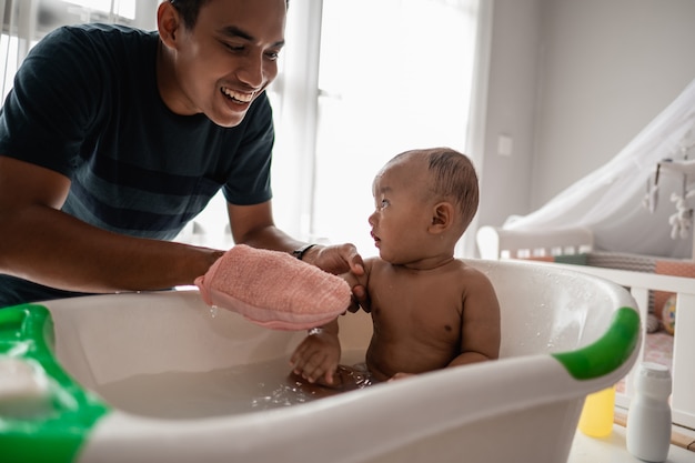 Aziatische vader die bad geeft aan zijn babypeuter