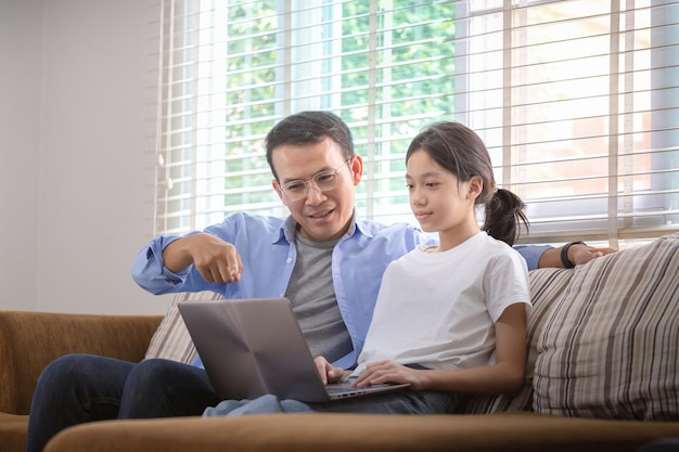 Aziatische vader en dochter die laptop thuis gebruiken Mensen die activiteiten en familieconcepten doen