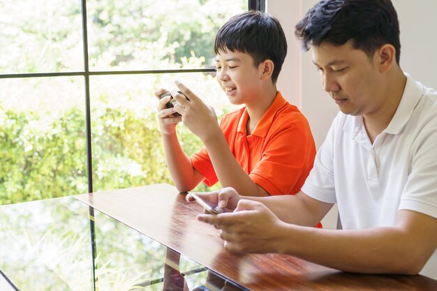 Aziatische vader en zoon met mobiele telefoon die samen games spelen vader brengt tijd door met kinderen familie
