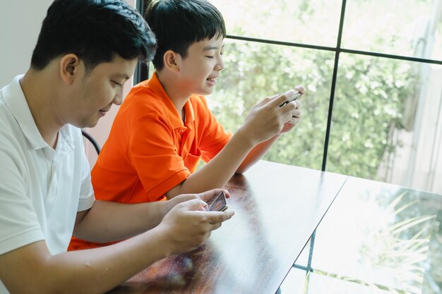 Aziatische vader en zoon met mobiele telefoon die samen games spelen vader brengt tijd door met kinderen familie