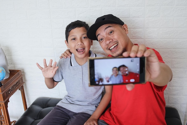 Aziatische vader geniet van het nemen van selfie met zijn zoon.