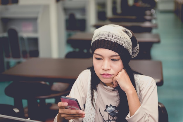 Aziatische verdrietig meisje kijkt naar haar telefoon in de bibliotheek vintage stijl Thaise vrouw stress van liefdesverdriet concept donkere toon