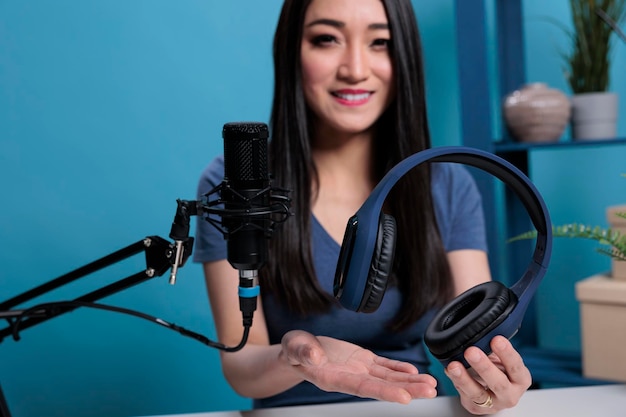 Aziatische vlogger-maker met headset die in studiomicrofoon praat met een abonnement voor het opnemen van hoofdtelefoons. Zelfstudie over het filmen van sociale media met professionele apparatuur in de studio