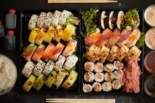 Aziatische voedselbezorging thuis verschillende sushi sets in plastic containers met sauzen rijst en eetstokjes Top view platte leg