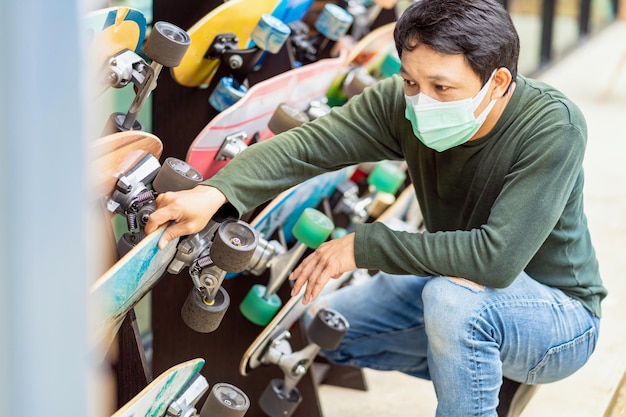 Aziatische vrolijke man die surfskate kiest om te testen en te skaten voor de surfskate-planeet x