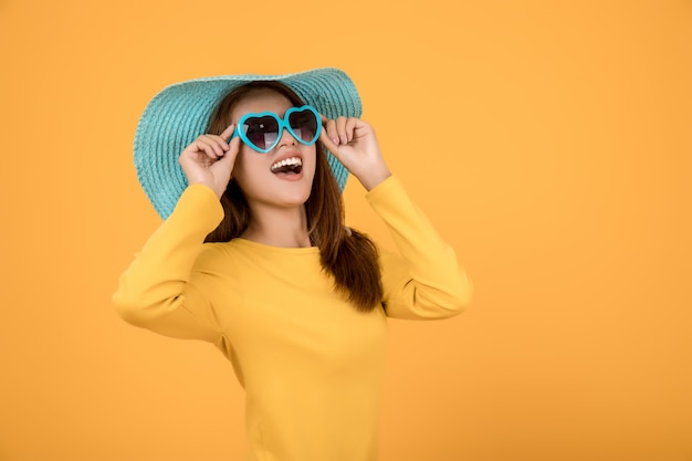 Aziatische vrouw aankleden concept Vakantie met een gele overhemd Zonnebril en hoeden zijn blauw en maken gezichten erg blij.