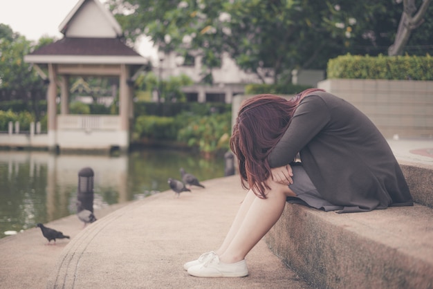 Aziatische vrouw alleen en gedeprimeerd zitten, portret van vermoeide jonge vrouw. depressie