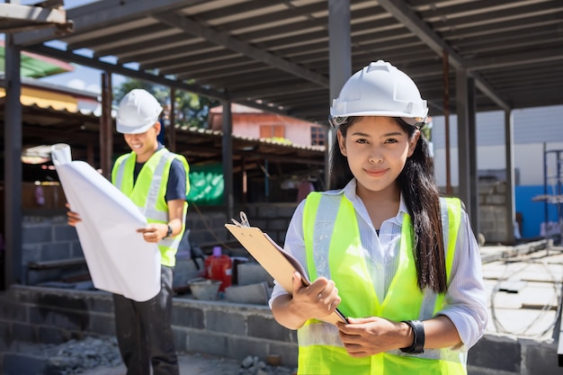 Aziatische vrouw burgerlijk ingenieur papier plan gebouw architect dragen witte veiligheidshelm kijken naar bouwplaats.