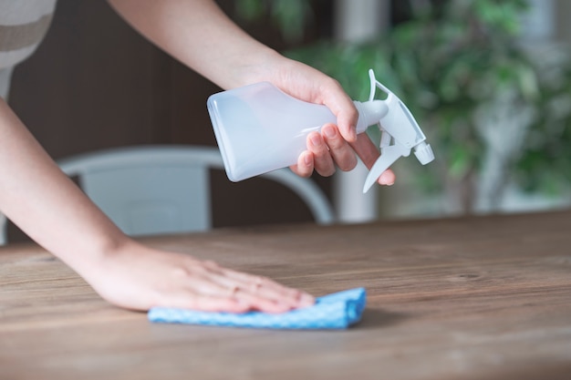 Aziatische vrouw desinfecteren huis eettafel met spray