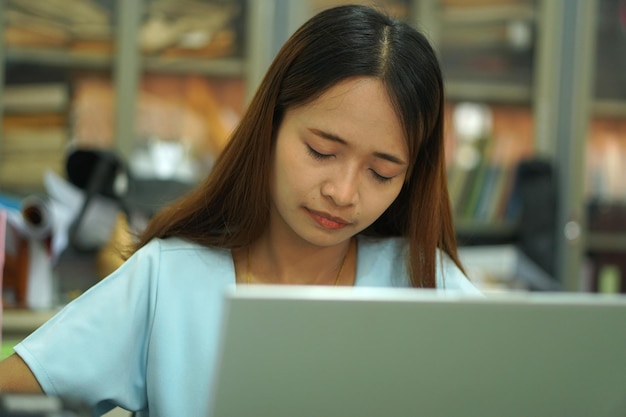 Aziatische vrouw die aan haar bureau slaapt van hard werken, maakt haar lichaam uitgeput