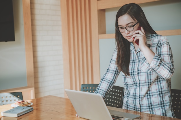 Aziatische vrouw die aan laptop en besprekingen werkt