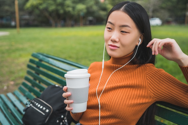 Aziatische vrouw die aan muziek luistert.