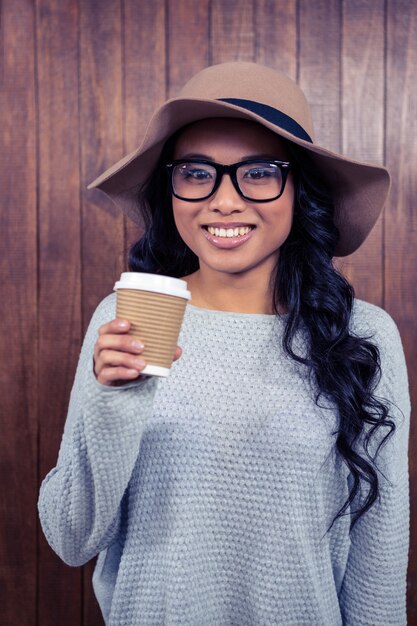 Aziatische vrouw die beschikbare kop houden tegen houten muur