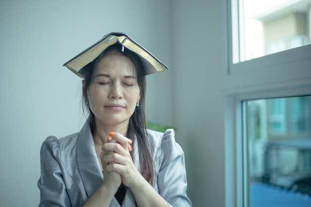 Aziatische vrouw die bidt en de bijbel op haar hoofd zet