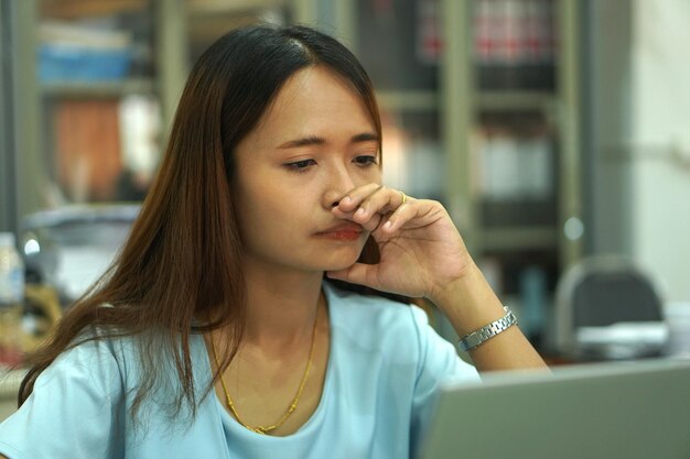 Aziatische vrouw die computer bekijkt Gefrustreerd door dalende inkomens