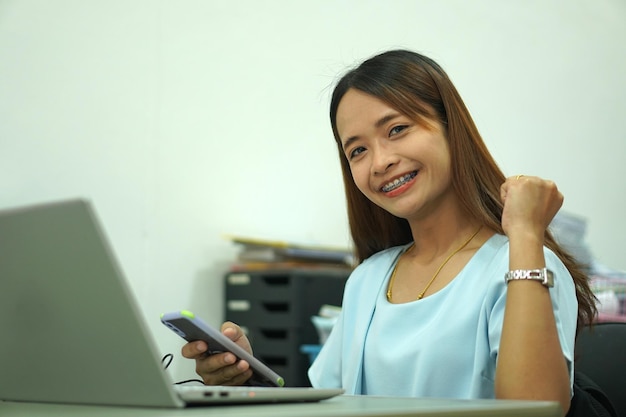 Aziatische vrouw die computer bekijkt Opgetogen van hogere inkomens