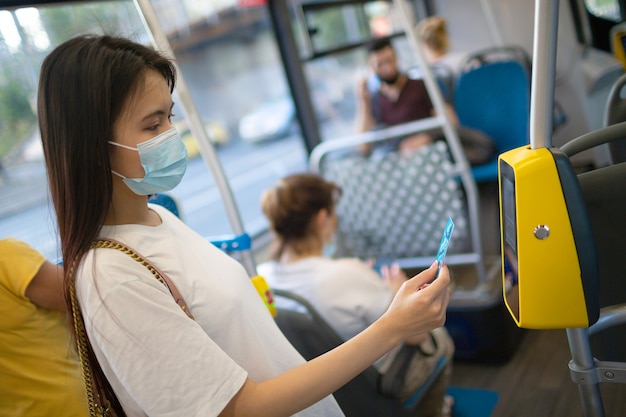 Aziatische vrouw die contactloos betaalt met een plastic kaart voor het openbaar vervoer in de bus