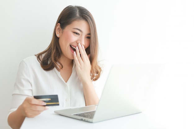 Aziatische vrouw die creditcard gebruikt die online met laptop computer winkelt,