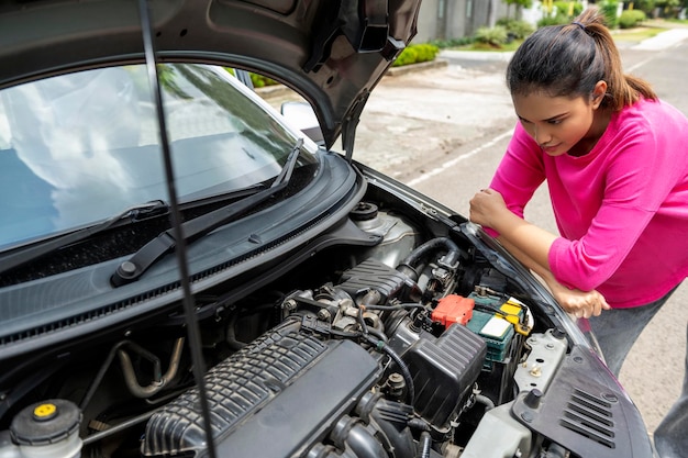 Aziatische vrouw die de motorkap opent en op zoek gaat naar problemen, de auto gaat kapot