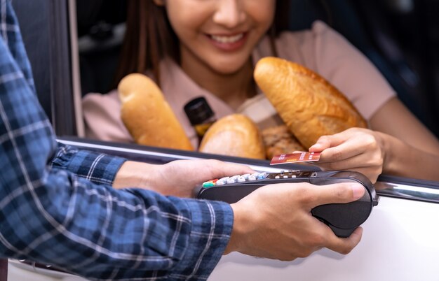 Aziatische vrouw die een creditcard houdt en uit de auto betaalt