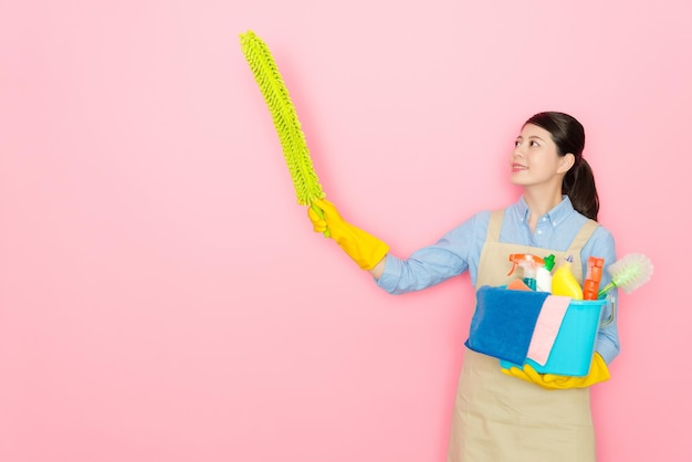 Aziatische vrouw die een gele verenstok vasthoudt en over de hele ruimte zwaait om de muur op te ruimen.