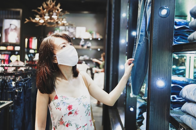 Aziatische vrouw die een gezichtsmasker draagt op een het winkelen plaats