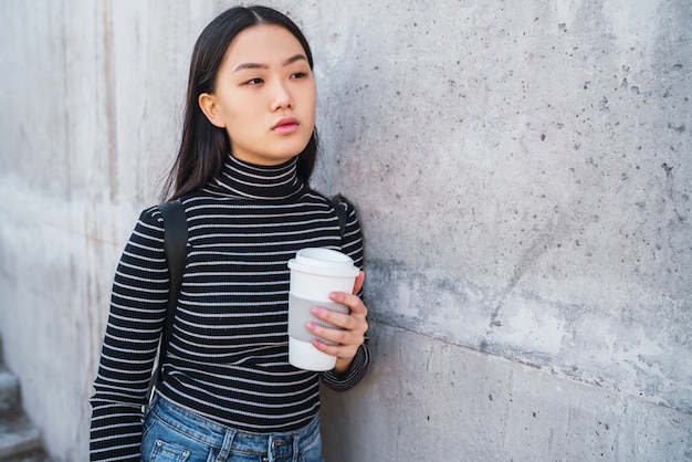 Aziatische vrouw die een kop van koffie houdt