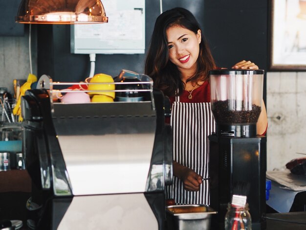 Aziatische vrouw die een kop van koffiekop maakt bij koffie