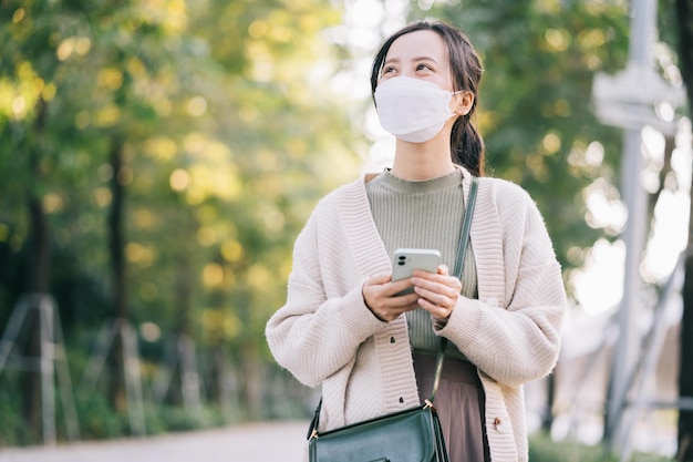 Aziatische vrouw die een masker draagt terwijl ze op straat loopt