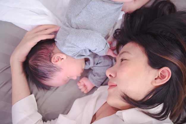 Aziatische vrouw die een pasgeboren baby thuis in haar wapens houdt.