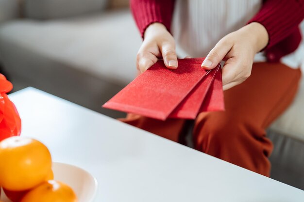 Aziatische vrouw die een rode envelop geeft voor de Lunar New Year-viering met een rood pakje in de hand