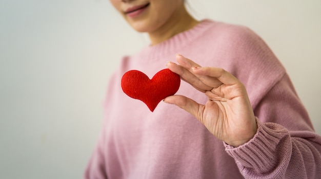 Aziatische vrouw die een rood hart in haar handen houdt.