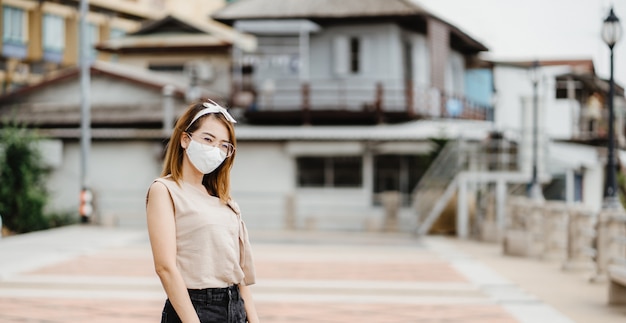 Aziatische vrouw die een wit masker draagt om het coronavirus te beschermen, een antivirusbeschermingsmasker met standaard om coronavirus te voorkomen COVID-19