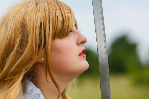 Aziatische vrouw die een zwaard in een strijderspositie houdt. Vechtconcept.