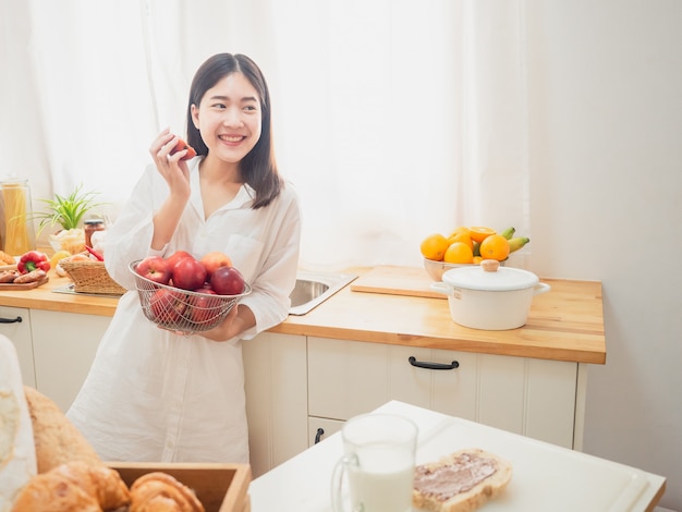 Aziatische vrouw die fruit in de keuken eet