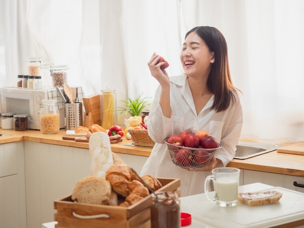 Aziatische vrouw die fruit in de keuken eet