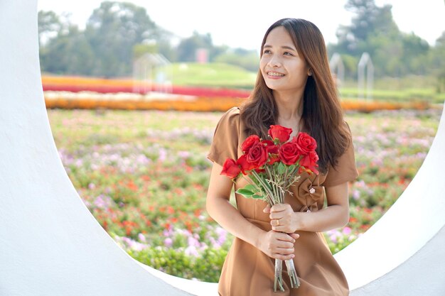 Aziatische vrouw die gelukkig lacht tussen prachtige bloemen