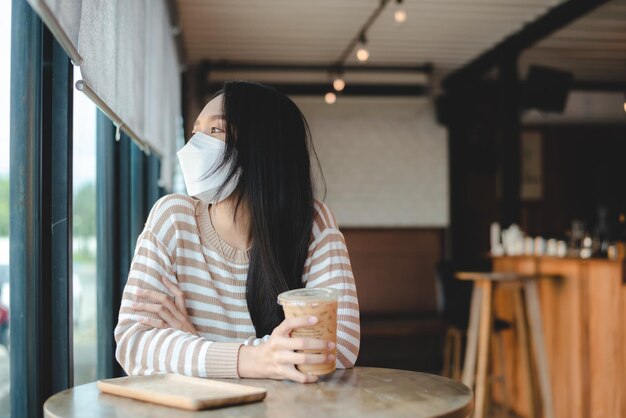 Aziatische vrouw die gescheiden zit in restaurant eten eten houdt sociale afstand om covid te voorkomen