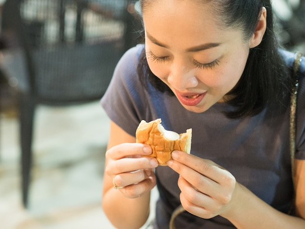 Aziatische vrouw die Gevulde romige broodjes eten.