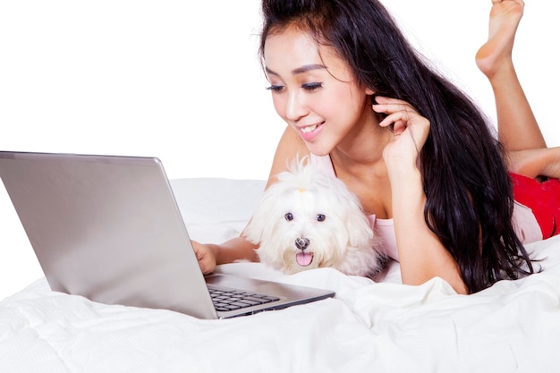 Aziatische vrouw die haar laptop met haar witte hond gebruikt