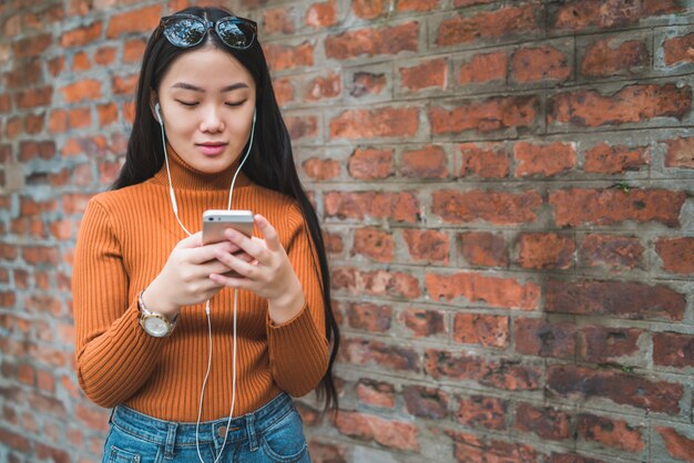 Aziatische vrouw die haar mobiele telefoon met behulp van.