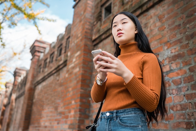 Aziatische vrouw die haar mobiele telefoon met behulp van.