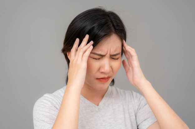 Aziatische vrouw die haar slaap vasthoudt en een slecht gezicht trekt vrouw met migrainehoofdpijn