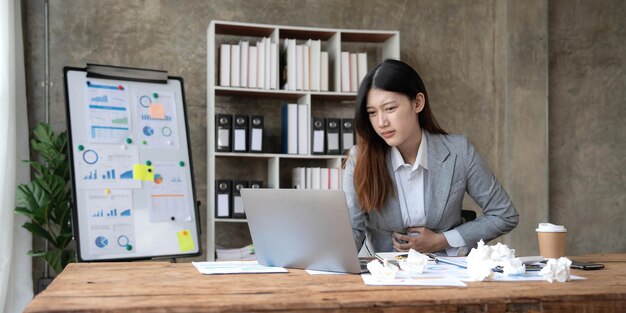 Aziatische vrouw die hard nadenkt bezorgd over online probleemoplossing die naar laptopscherm kijkt bezorgd ernstige Aziatische zakenvrouw gericht op het oplossen van moeilijke werkcomputertaak