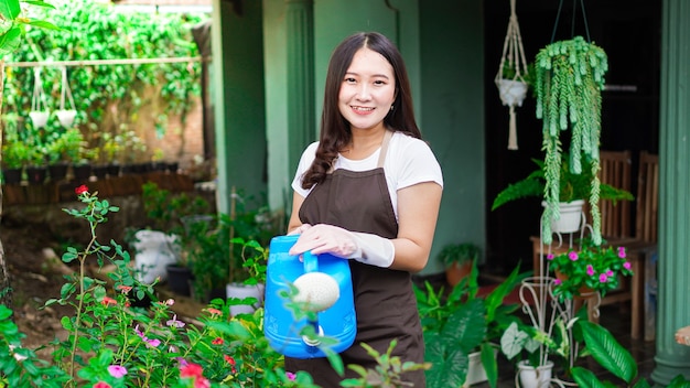 Aziatische vrouw die het water geven bloem thuis tuin verzorgen